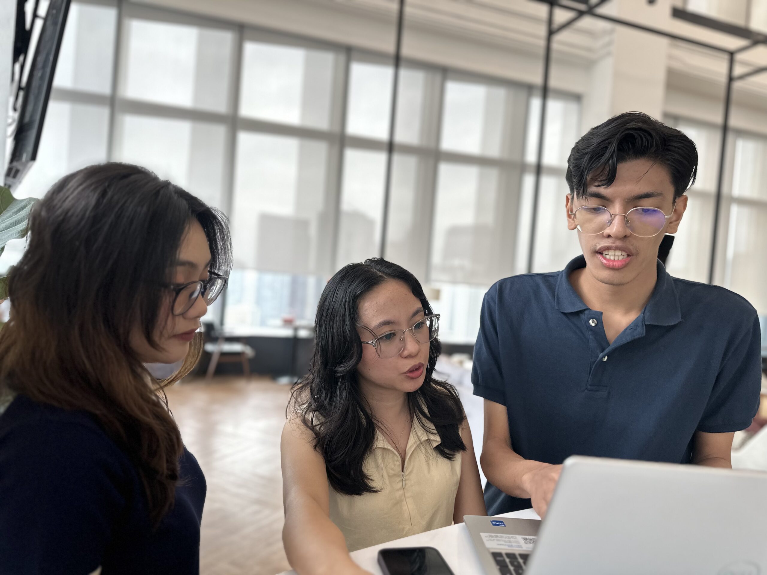 Denova team members collaborating around a laptop